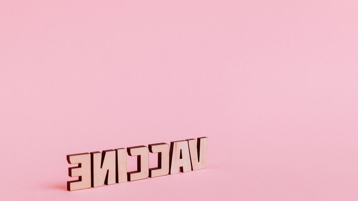 Vaccine lettering on soft pink background, highlighting healthcare concepts.