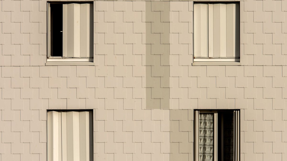 Proper Cladding Installation Requires Careful Planning Close-up of a modern apartment building facade with symmetrical windows and beige cladding.