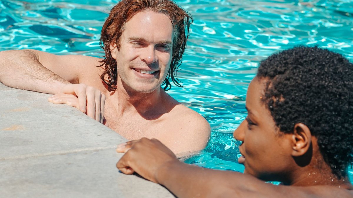 Two friends relaxing and chatting at a swimming pool during a sunny day. Enjoyment of vacation.