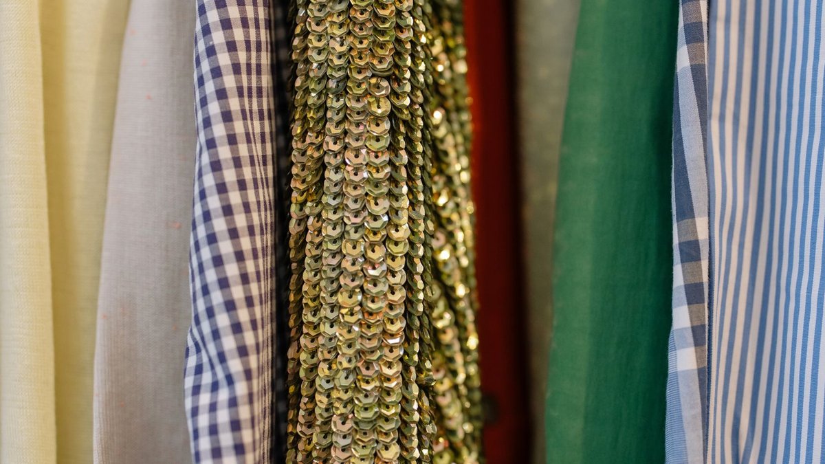 African designers turn local fabrics into global fashion statements Close-up of assorted fabrics including sequined and patterned textiles on display in a retail shop.