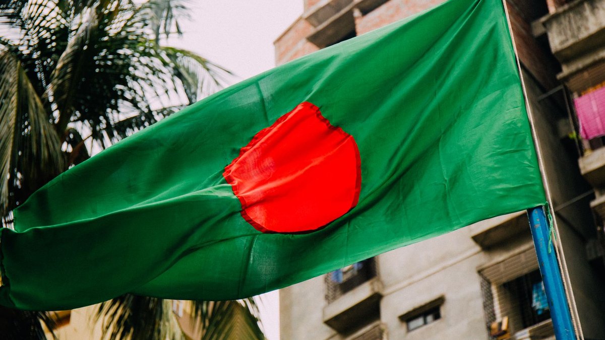 Bangladesh-China Trade Hits $12.8 billion in H1 2026 A vibrant Bangladesh flag waving against a cityscape backdrop, evoking patriotism.