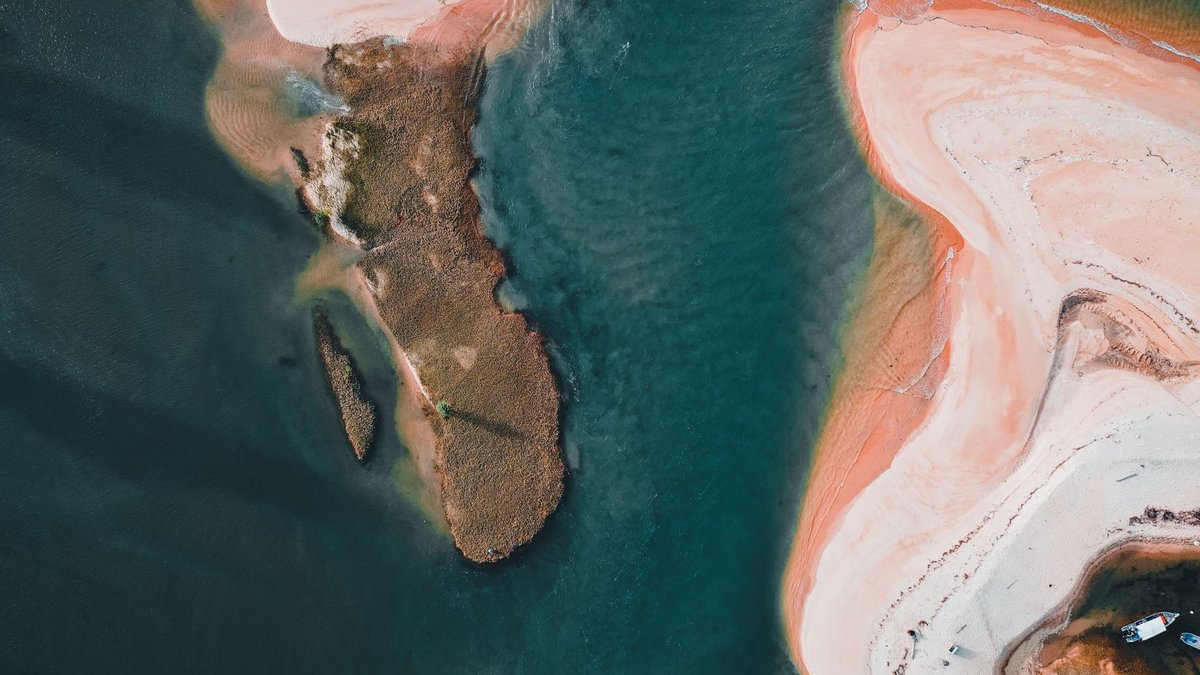 A stunning aerial view of an island's shoreline with vivid sea colors.