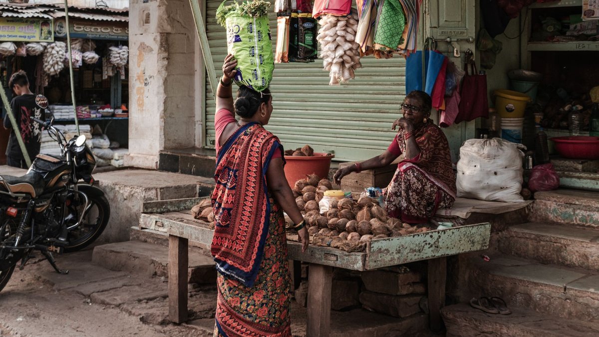 Authentic Indian market stall with women in traditional attire interacting. Vibrant cultural snapshot.