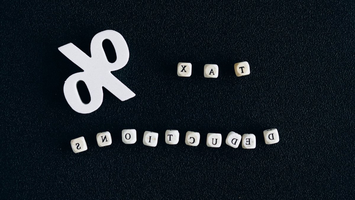 Conceptual image of tax deductions with alphabet blocks and percent symbol on black surface.