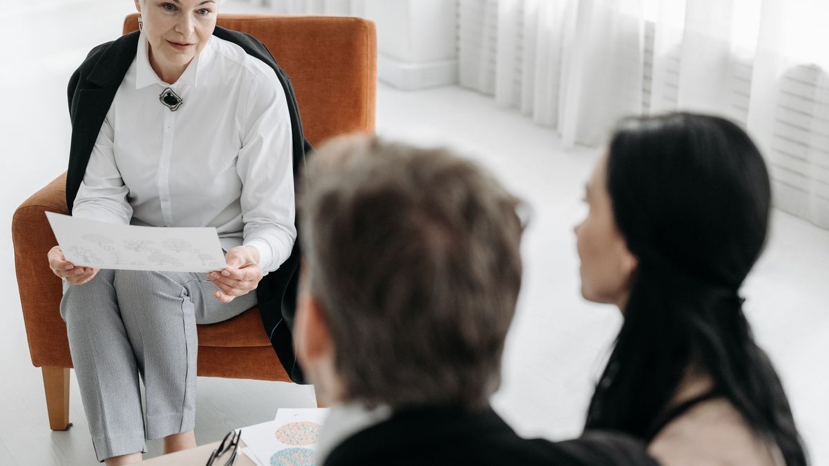 Professional advisor discussing documents with a couple in a modern office setting.