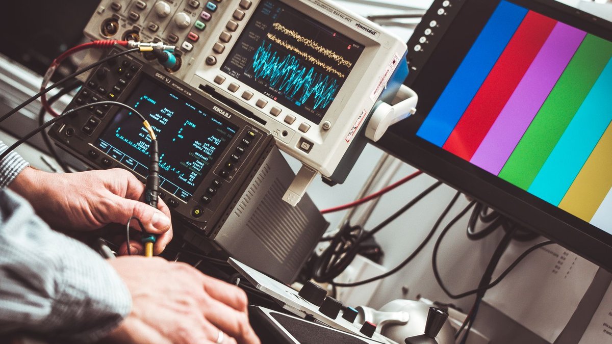 Technician operating laboratory electronic testing and measurement devices with colorful display.