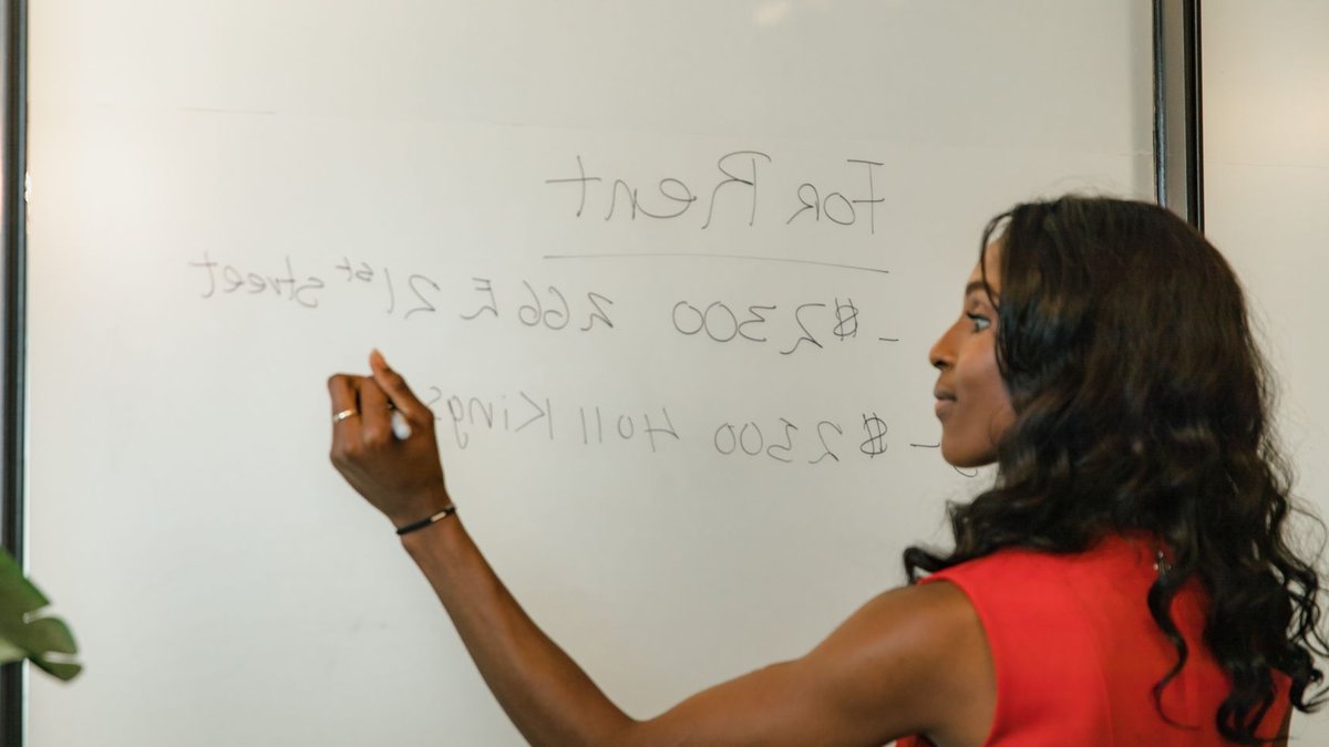 Professional woman writing real estate prices on a whiteboard for rental properties.