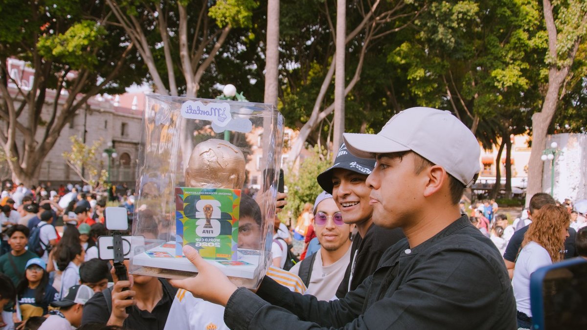 FIFA World Cup Expands to 48 Teams Group of people celebrating with a FIFA World Cup trophy replica in a vibrant outdoor setting.