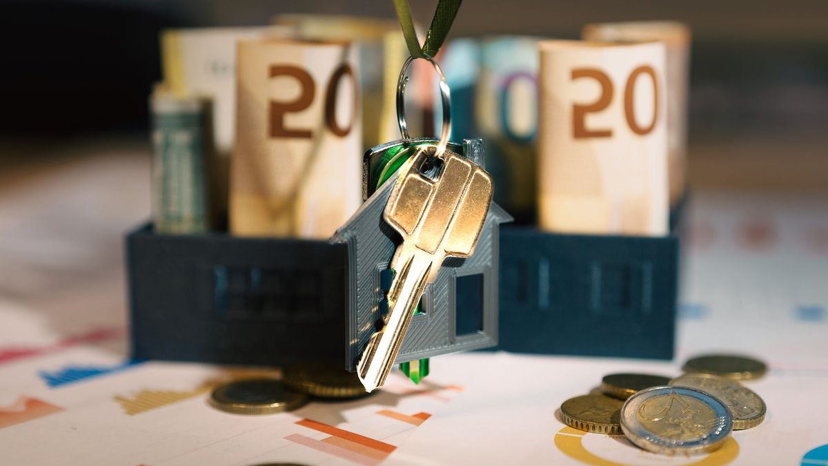 Keys hanging with money and charts, symbolizing real estate investment and financial planning.