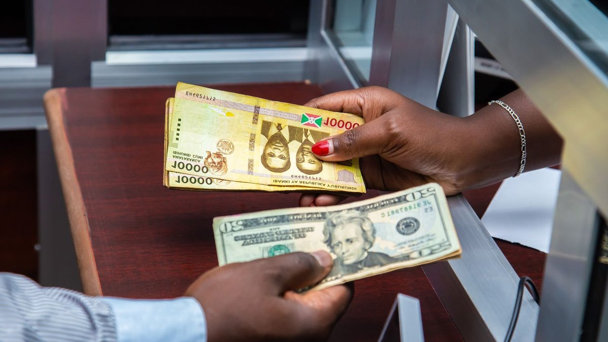 Burundian franc and US dollar exchange transaction at bank counter.
