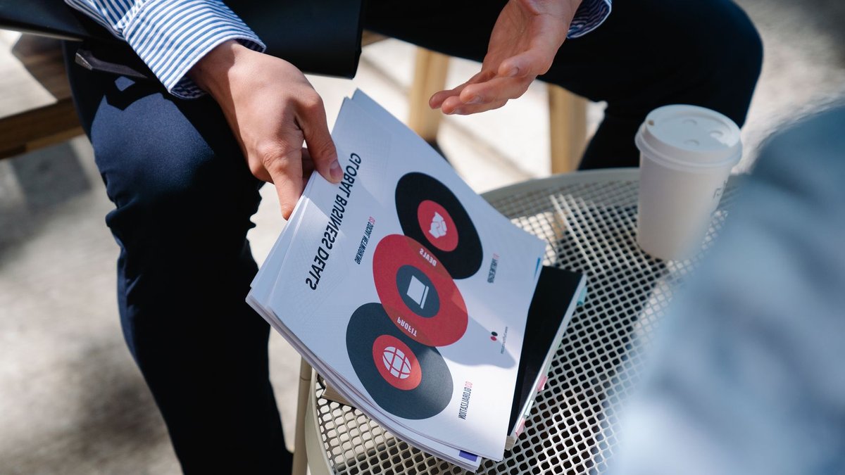 A businessman discusses global business deals with visual aids during an outdoor meeting.