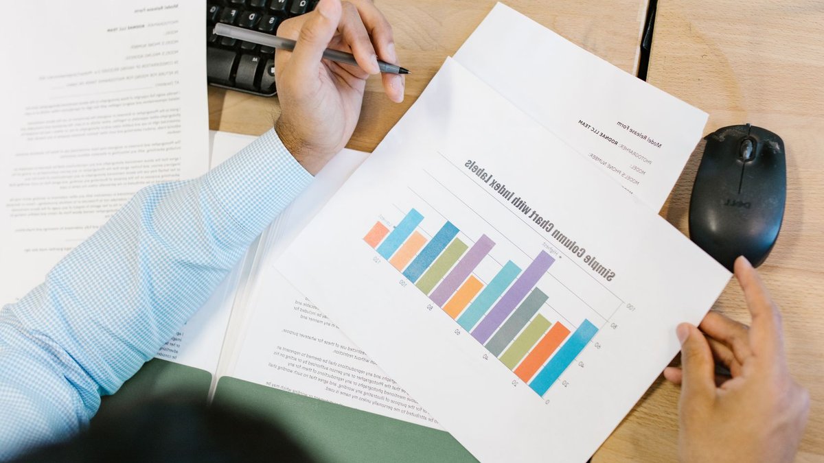 Palliser urges Samsung, Hyundai to close preferred share discounts A business analyst reviews a colorful bar chart and documents at a desk, indicating data analysis.