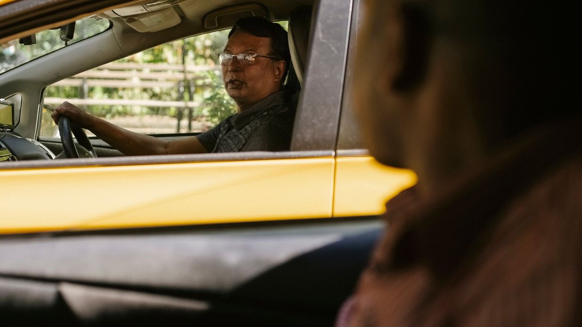Multiracial male drivers sitting in cabs with opened windows and talking while working and looking at each other.