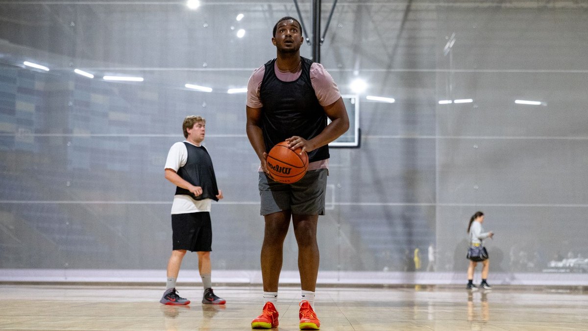 Mavericks Waive Powell, Retain Cisse Amidst NBA Interest Group of young adults playing basketball on an indoor court, focusing on a player preparing to shoot.