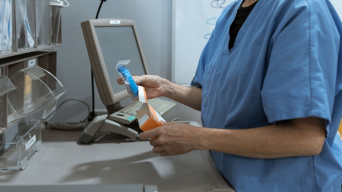 Healthcare worker in scrubs organizing medication in a medical facility.