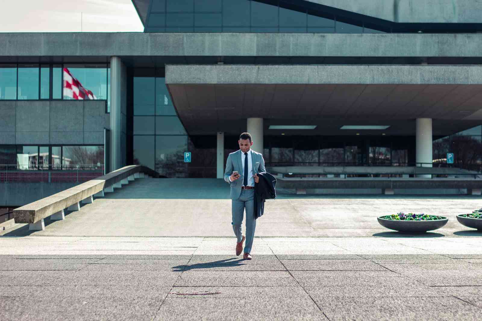 Man using a phone while walking away from a building