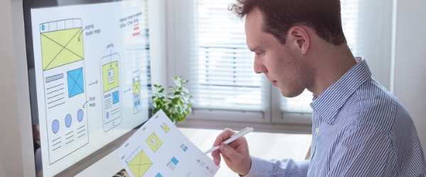 A web designer sitting at his desk looking over designs.