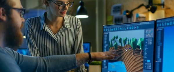 Two video game designers looking at the computer screen and discussing game development.