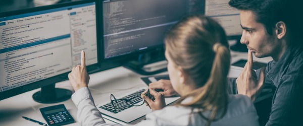 Two systems architects looking at a computer and discussing how best to maintain a company's computer systems.