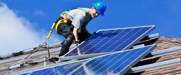 A solar thermal installer installing solar panels on a roof.