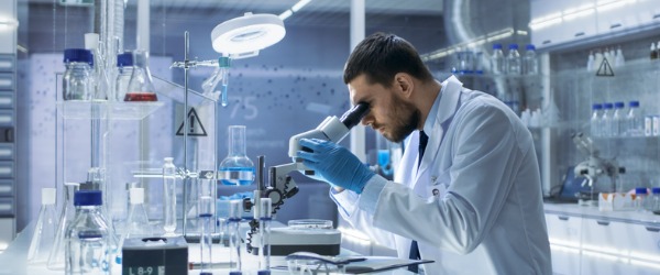 A scientist looking through a microscope in a labratory.