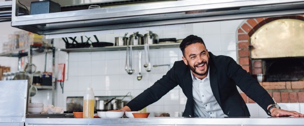 Een restaurantmanager lacht in de keuken.