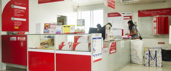 A postal service clerk tabulating the correct amount of postage required for a customer.