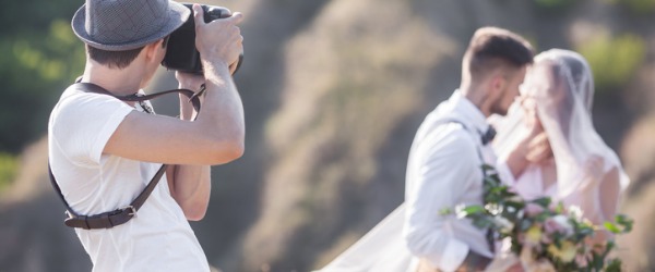 A photographer taking a picture of a bride and groom.