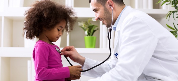 A pediatrician using a stethoscope to check a little girl's heartbeat.