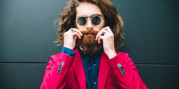A male model wearing sunglasses and a red jacket posing for the camera.