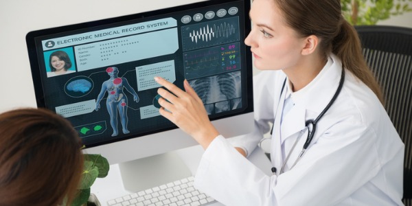 Ein medizinischer Aufnahmetechniker schaut sich am Computer die medizinischen Aufzeichnungen eines Patienten an.