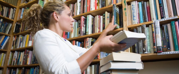 A librarian putting books back on a bookshelf.