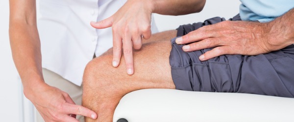 Un kinesiólogo que aplica pruebas musculares a la rodilla de un paciente.'s knee.