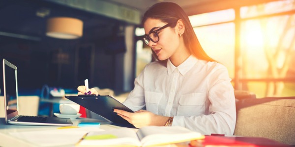 A graduate teaching assistant grading papers at a desk.