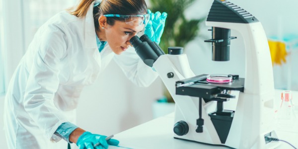 A geneticist looking through a microscope.