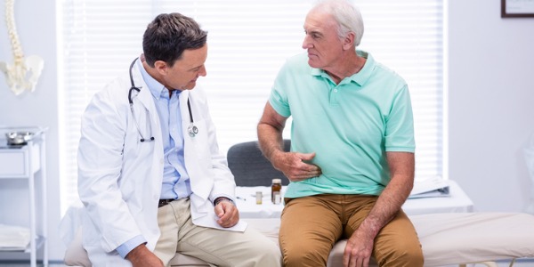 A gastroenterologist listening to a patient describe the discomfort he is experiencing in his GI tract.