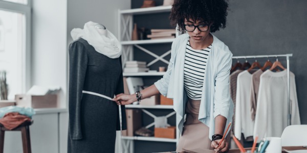 A fashion designer measuring the waist of a dress on a mannequin.