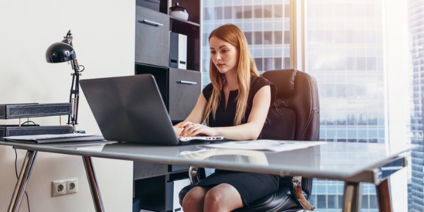 An executive assistant sitting at her desk and working on her computer.