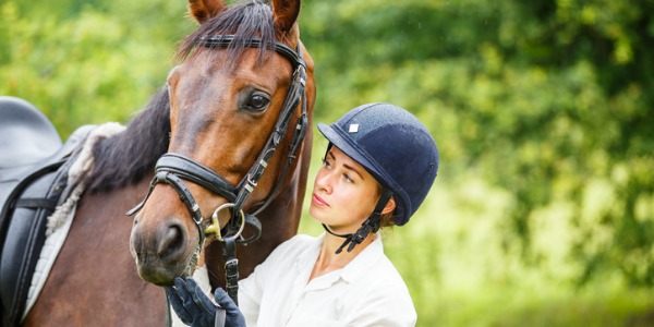 An equestrian outside with her horse.