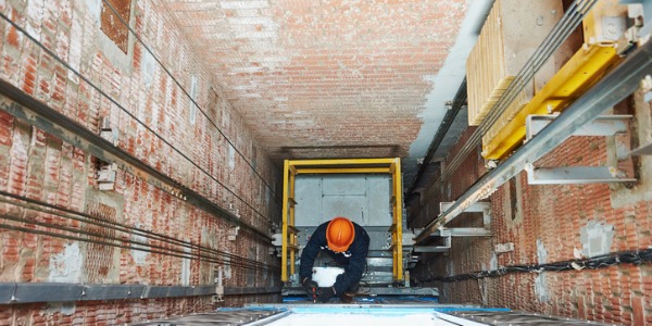 An elevator mechanic fixing an elevator.