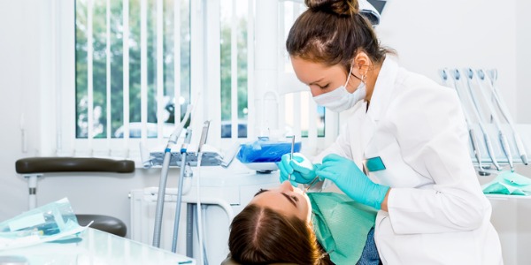 A dental hygienist cleaning a patient's teeth.