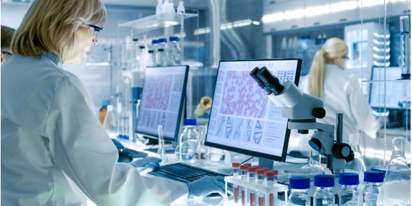 A cytogenetic technologist looking at medical images on her computer.
