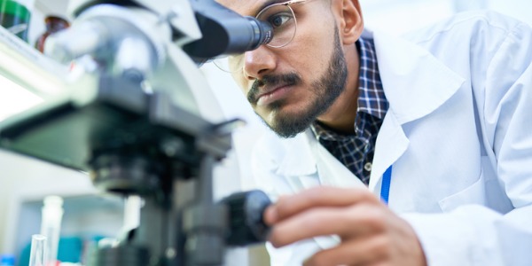 A cytotechnologist using a microscope to evaluate the health of cells.