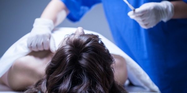 A coroner examining a body in the morgue.