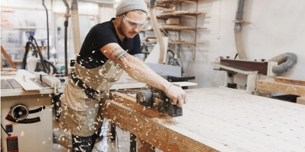 A carpenter working inside a woodworking shop.