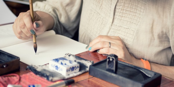 A calligrapher uses an instrument like a paint brush, pen, or marker to create a particular style of writing that is artistic and expressive.