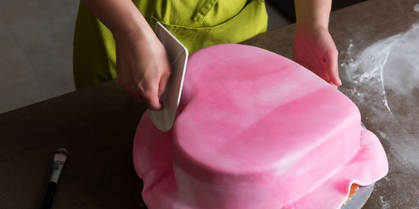 Cake designers manipulate the frosting or fondant to create a custom designed cake based on instructions provided by the customer.