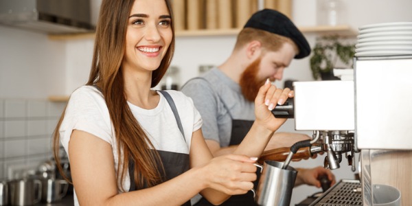 A barista preparing and serving an espresso-based coffee drink.
