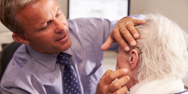 An audiologist fitting a hearing aid for an elderly patient.