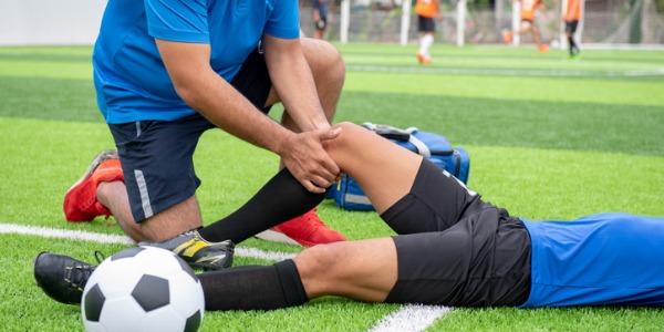 An athletic trainer out on a soccer field providing care for an injured soccer player.